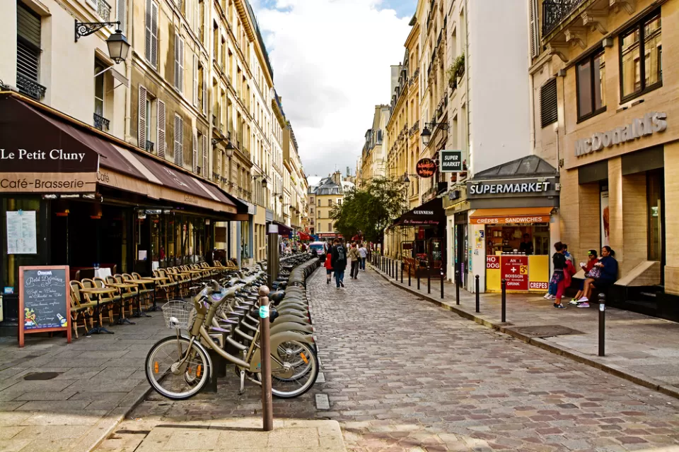 Street in Paris Latin Quarter with row of bicycles, cobblestone street, and pedestrians